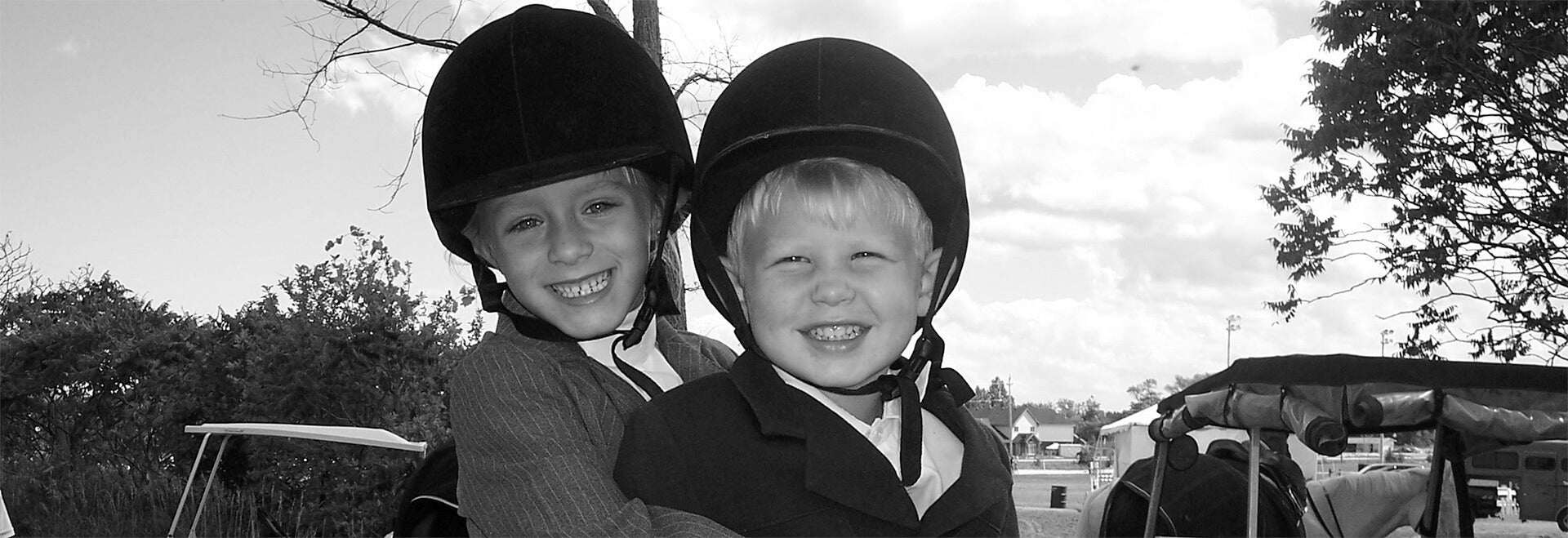 Two children smiling while sitting on a horse